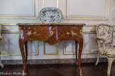 Musée des Arts Décoratifs. Salon de compagnie<br> La commode en table d’applique, très beau meuble d’ébénisterie parisienne, à la marqueterie d’acajou ronceux, bois de rose et violette, ouvrant à un seul tiroir, est décorée de bronzes dorés au poinçon du C couronné qui permettent de la dater entre 1745 et 1749.