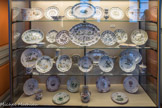 Musée des Arts Décoratifs. Première antichambre<br> Moustiers du XVIIIème siècle. Grand feu. Les pièces sont décorées pour la majorité d'entre elles dans la polychromie de grand feu, une petite minorité étant peinte en camaïeu de bleu, vert et manganèse. Les différents décors illustrés dans cette vitrine ont été largement utilisés et appréciés dans la seconde moitié du XVIIIème siècle.
 - Décor « à guirlandes et médaillons » : un des plus raffinés de la faïence moustérienne. 
- Décor « à grotesques » : le plus souvent reproduit à Moustiers, il interprète, avec une fantaisie toute méridionale, les modèles de Callot, traité en camaïeu et en polychromie jaune et verte (deuxième étagère en partant du haut).
- Décor « aux drapeaux » : plat présenté sur la troisième étagère, créé, selon la tradition, au lendemain de la bataille de Fontenoy (1745).
- Le motif dit improprement 