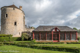 Le château de Montaigne.<br> Le bâtiment percé de grandes baies vitrées est l’orangerie, serre construite par Pierre Magne, propriétaire du château au XIXème siècle. L'orangerie est bâtie contre une muraille, vestige de la forteresse du XIVème siècle, qui ferme la 