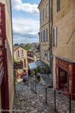 Saint-Emilion. <br> Un tertre est définit comme étant un monticule de terre, une butte. Il prend tout son sens à Saint-Emilion où le site est naturellement doté de pentes. Le village a en effet su s’adapter en modelant son relief avec des tertres désignant ces ruelles typiques de la cité, pentue et au pavage irrégulier. Quatre tertres permettent de relier les deux parties de la ville : la ville haute et la ville basse.
