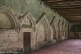 Saint-Emilion. L’ensemble Collégiale.<br> Le cloître. Les murs sud et est du cloître furent ensuite modifiés pour recevoir dans des niches en arc brisé, plus ou moins profondes et plus ou moins décorées, une série de tombeaux. Deux gisants très mutilés y sont conservés.
Au sud, se succèdent dix ouvertures surmontées de gâbles à crochets, dont les arcs trilobés sont inscrits dans des arcs brisés. Une sculpture très fine garnit l’ensemble, y compris les écoinçons : ce sont des feuilles, de petits animaux, des fleurs ou des masques humains. Les chapiteaux des colonnettes reçoivent des feuillages stylisés.
L’un des enfeus possède un décor historié : des anges alternent avec des vierges sages tenant leur coupe, à gauche, et des vierges folles, à droite, renversant ces mêmes coupes.
La sculpture d’un très bon style, montre des corps déhanchés, des têtes rondes aux yeux en amande et à l’abondante chevelure ondulée.