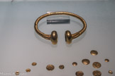 Musée d'Aquitaine. <br> Le torque lui-même a été réalisé à partir d’une tige dont la section, en forme de croix, a été tordue tout le long afin de produire un effet spiralé. Les extrémités rajoutées (tampons), de grande dimension, sont creuses. Le décor qui les jouxte simule des grènetis, assurant une liaison esthétique avec les spirales du bijou.