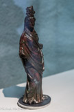 Musée d'Aquitaine. <br> Isis-Fortune
Bordeaux Époque romaine
Alliage de cuivre, et argent pour le blanc des yeux
Isis-Fortune est une des représentations de la déesse qui se retrouve assez couramment dans les ports. Elle dénote bien le syncrétisme oriental et romain : la coiffe est celle de l’Isis égyptienne (disque lunaire et cornes d’Hathor), mais - si ce ne sont les plumes de Maat les épis de blé sont là pour indiquer qu’elle représente aussi une déesse d’abondance, comme le confirmait la corne d’abondance qu’elle devait tenir en main gauche. Elle représente la déesse Fortune qui pilote les marins et qui est célébrée en procession lors de la fête du navigium Isidis, ce qui explique le gouvernail qu’elle tenait en main droite