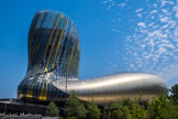 La Cité du Vin<br> La Cité du Vin a ouvert ses portes en juin 1016. Imaginée par l'agence XTU architects, son architecture audacieuse marque par ses formes mouvantes qui évoquent l'univers du vin. Sa couleur mordorée et ses reflets changeants répondent au fleuve et à la pierre de Bordeaux. Le bâtiment se déploie sur près de 14 000 m2. Son ossature comporte 574 arches de bois, sa « peau » est constituée de 2 500 écailles d’aluminium perforé et de 900 panneaux de verre sérigraphié. Le patio apporte de la lumière au cœur de l’édifice. La tour qui culmine à 55 m de haut offre un point de vue inédit sur la ville.