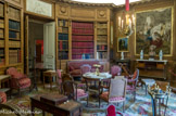 <center>Musée Nissim de Camondo</center>La bibliothèque. Dans cette pièce en rotonde qui occupe le centre des appartements privés de l’hôtel, les boiseries en chêne naturel sculpté ont déterminé la hauteur de cet étage et créent une atmosphère chaleureuse. C’est ici que Moïse de Camondo consultait ses catalogues de ventes et de nombreux périodiques dont la Gazette des Beaux-Arts qu’il faisait soigneusement relier en maroquin rouge. Petit tableau, Pavillon rustique dans un parc, par Hubert Robert, huile sur toile. A droite, banquette, ateliers royaux espagnols, vers 1790 – 1800, noyer plaqué d’ébène, amarante, houx, acajou, bronze ciselé doré, couverte en tapisserie.