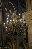 <center>Lustre.</center> Au XIXe siècle, Notre-Dame de Paris avait perdu sa grande Couronne de lumière et Viollet-le-Duc avait notamment pour mission de reconstituer le mobilier gothique du sanctuaire. Il s’attacha à élaborer les dessins d’une nouvelle Couronne dans le style gothique. La Couronne de lumière actuelle est à deux rangs surmontée de tourelles en cuivre doré. Elle a été exécutée à l’époque par l’orfèvre Placide Poussielgue-Rusand. 
Quant aux autres lustres de la nef de la cathédrale, ils sont en bronze doré et datent de la même époque