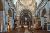<center>Notre-Dame-des-Victoires. </center> La longueur totale de l'église est de 62 mètres pour une largeur de 24,50 mètres. La hauteur de la voûte est de 15 mètres. L'église est de style classique. On remarque la corniche à modillons et roses, et ses pilastres d'ordre ionique. A droite,Le banc d'œuvre. Œuvre de Grienwald, 1864. Sur les pilastres, le chemin de croix, en lave émaillée, date de 1872-1874.