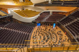 <center>Philharmonie de Paris</center> La Philharmonie 1. La scène offre la possibilité d’accueillir tous les types de formations orchestrales, même les plus imposantes. En configuration symphonique, les spectateurs entourent l’orchestre. Les places situées derrière la scène, en gradin, accueillent un chœur si l’œuvre interprétée l’exige ou, le plus souvent, du public. Ces gradins arrière sont escamotables, ce qui permet de reculer la scène et d’agrandir le parterre