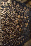 <center></center><center>Les Catacombes de Paris. </center> Les ossements, précédemment laissés en vrac, sont soigneusement organisés en murs, sur le modèle des hagues de carriers. En façade, les rangées de tibias alternent avec celles de crânes, tandis que derrière les parements s’entassent les os restants, souvent très fragmentés par les conséquences de leur chute.