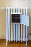 <center>Conflans : Musée d’Art et d’Histoire.</center> Radiateur chauffe-plat. Fonte.
Le chauffage central fait son apparition dans les intérieurs français vers les années 1880 et se généralise après 1930. Grâce à l'emploi de la fonte et à leur contenance importante, les radiateurs en fonte possèdent une forte inertie thermique : ils refroidissent très lentement après la coupure du système de chauffage. Ces propriétés expliquent qu'ils sont parfois utilisés comme chauffe-plat.
